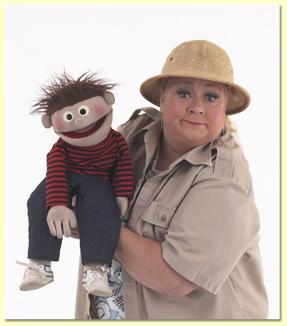 Big photo of Margaret Clauder, ventriloquist and puppeteer, dressed as Paleo-Maggie with her puppet, Elmer.