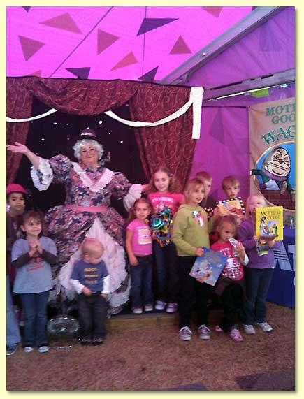 Photograph of Mother Goose performed by Margaret Clauder, with children holding Mother Goose books.